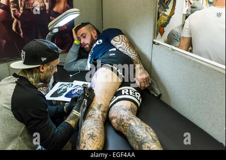 Un homme d'être tatoué sur sa jambe à la Convention de tatouage de Brighton. Banque D'Images