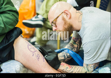 Un homme d'être tatoué sur sa jambe à la Convention de Tatouage de Brighton. Banque D'Images