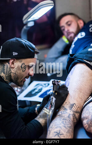 Un homme d'être tatoué sur sa jambe à la Convention de Tatouage de Brighton. Banque D'Images