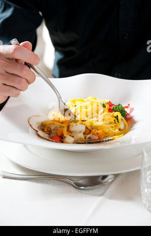 Man eating Spaghetti aux légumes et poisson Banque D'Images