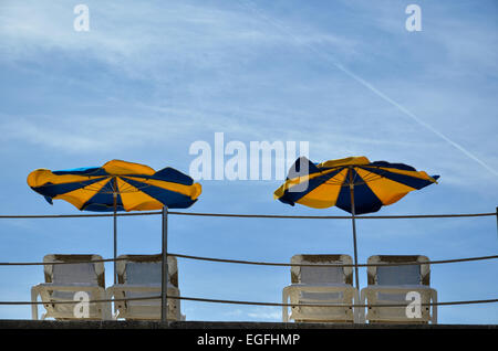 Des parasols et transats à ciel bleu Banque D'Images