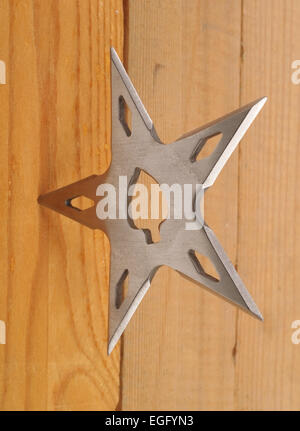 Lame de ninja Shuriken lancer star en planche de bois, studio shot Banque D'Images