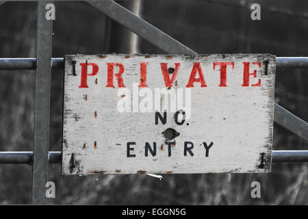 Pas d'entrée privée signe sur metal gate avec des lettres rouge et noir sur blanc se détachant sur fond monochrome Banque D'Images