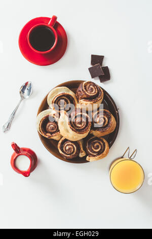 Pâtisserie au chocolat, tasse de café et jus d'orange sur fond blanc d'en haut Banque D'Images