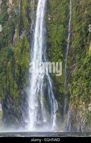 Milford Sound Stirling Falls avec quatre petits kayaks de mer jaune sous la haute cascade. Parc National de Fiordland en Nouvelle-Zélande. Banque D'Images