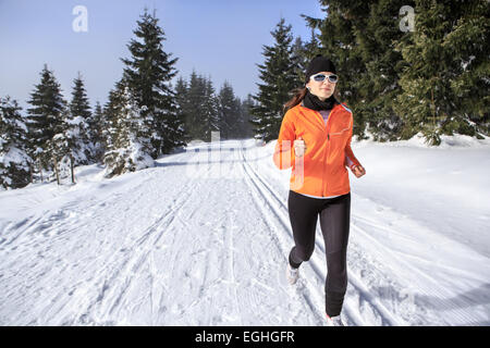 Une jeune femme le jogging dans la forêt d'hiver Banque D'Images