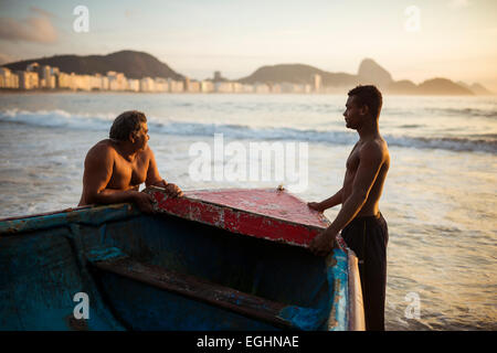 Les pêcheurs de prendre leurs bateaux à l'aube, la plage de Copacabana, Rio de Janeiro, Brésil Banque D'Images