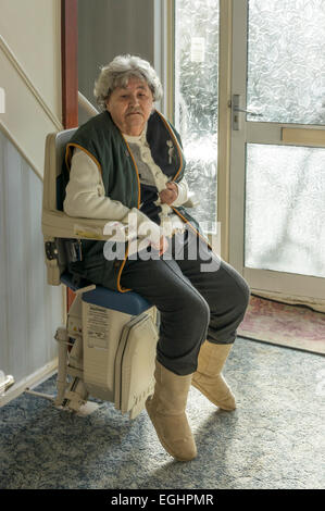 Une vieille dame à l'aide d'un monte-escalier pour monter dans sa propre maison. Banque D'Images