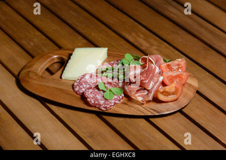 Conseil d'Antipasti Tapas : Jambon Serrano, Salchicon salami, salade de tomates et fromage Manchego décoré de feuilles de pois vert. Banque D'Images