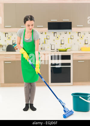 Young caucasian woman standing dans la cuisine à la maison, laver des planchers avec RDP Banque D'Images