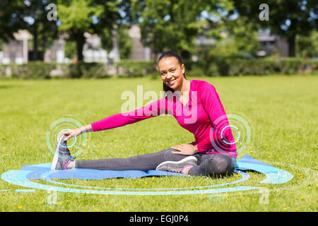 Smiling woman stretching leg sur mat à l'extérieur Banque D'Images