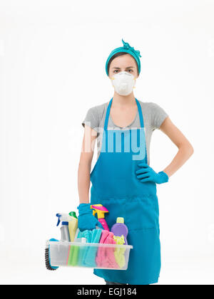 Jeune femme portant un masque de protection et holding basket avec fournitures de nettoyage, sur fond blanc Banque D'Images