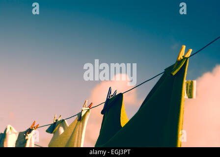 Vue rapprochée de vêtements sur une corde à linge avec des pinces à linge au coucher du soleil Banque D'Images