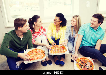 Cinq adolescents souriants de manger une pizza à la maison Banque D'Images