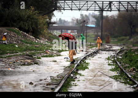 Peshawar, Pakistan. Feb 25, 2015. Un garçon de l'école traverse une voie de chemin de fer gorgé d'eau après de fortes pluies dans le nord-ouest de Peshawar au Pakistan, le 25 février 2015. Au moins deux femmes ont été tués alors qu'un toit d'une maison effondrée à Peshawar. Les fortes pluies ont causé des ravages dans différentes régions du Cachemire, Khyber Pakhtunkhwa et Gilgit-Baltistan mercredi, les médias locaux ont rapporté. Credit : Umar Qayyum/Xinhua/Alamy Live News Banque D'Images