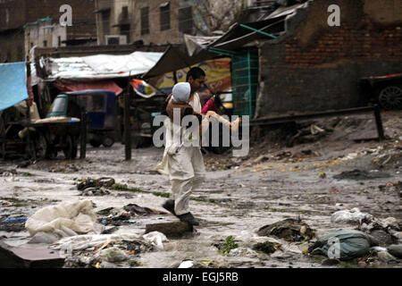 Peshawar, Pakistan. Feb 25, 2015. Un homme porte un enfant comme il traverse une rue gorgé d'eau après de fortes pluies dans le nord-ouest de Peshawar au Pakistan, le 25 février 2015. Au moins deux femmes ont été tués alors qu'un toit d'une maison effondrée à Peshawar. Les fortes pluies ont causé des ravages dans différentes régions du Cachemire, Khyber Pakhtunkhwa et Gilgit-Baltistan mercredi, les médias locaux ont rapporté. Credit : Umar Qayyum/Xinhua/Alamy Live News Banque D'Images