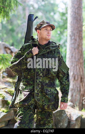 Jeune soldat ou un chasseur avec fusil en forêt Banque D'Images