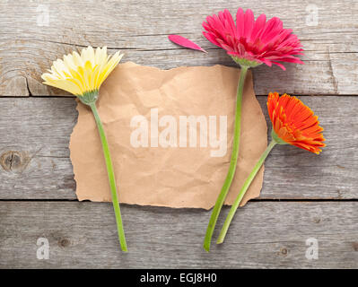 Trois gerbera coloré avec du papier pour la copie de l'espace sur une table en bois Banque D'Images