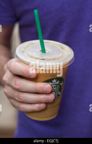 Homme tenant un café glacé Starbucks. Banque D'Images