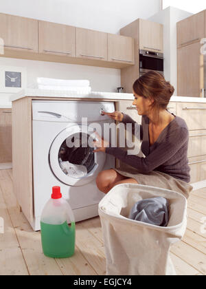 Jeune femme Chargement du lave-linge dans la pièce Banque D'Images