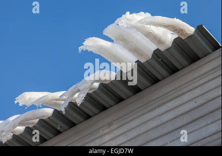 Gros glaçons pendant sur le toit de la maison au printemps Banque D'Images