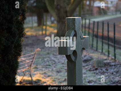 Frost couverts de pierres tombales et un siège à moitié caché dans un cimetière de village dans le Herefordshire, au Royaume-Uni, à l'aube d'un matin d'hiver gelé. Banque D'Images