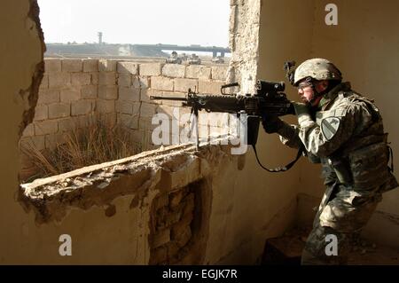 Un des soldats américains de la 1ère Division de cavalerie veille pour cibles des insurgés d'une fenêtre au cours d'une recherche d'un soldat disparu le 23 février 2007 à Bagdad, Iraq. Banque D'Images