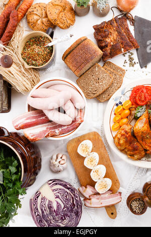 La table de divers type de plat comme saucisse polonaise lard fumé rôti de viande cuisse de poulet aux herbes pain œufs durs sur la nappe Banque D'Images