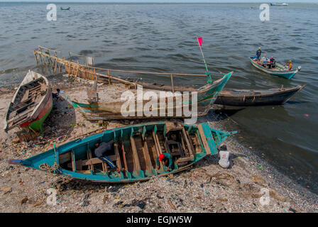 Les pêcheurs qui réparent un bateau en bois sur un terrain de Djakarta Nord, Indonésie. Banque D'Images