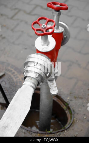 Détail tourné avec un tuyau flexible blanc connecté à un poteau rouge Banque D'Images