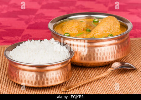 Poulet au curry indien servi avec du riz dans les authentiques des ustensiles de cuivre. Piment vert utilisé comme garniture. Profondeur de champ. Banque D'Images