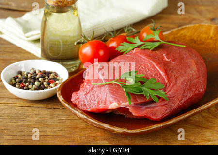 La viande de boeuf cru frais avec du poivre et des herbes sur plaque de bois Banque D'Images