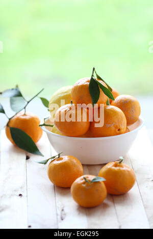 Les mandarines, les agrumes dans un bol sur une planche en bois Banque D'Images