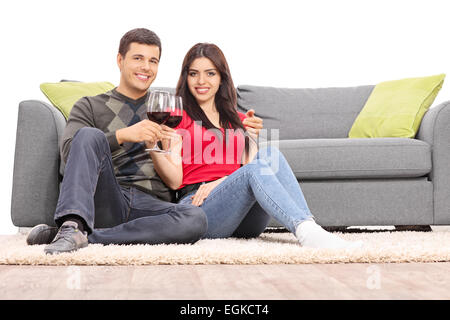 Jeune couple drinking wine assis par un canapé isolé sur fond blanc Banque D'Images