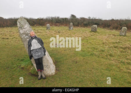 Une femme s'appuie sur la pierre centrale de l'ONU à Boscawen stone circle à Cornwall, UK Banque D'Images