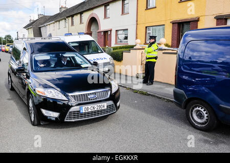 Bailieborough, comté de Cavan, République d'Irlande, 6 septembre 2013 - un corbillard s'arrête à une maison étant gardé par un officier Garda Siochana après qu'un corps avait été trouvé. Banque D'Images