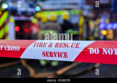 Fire Brigade place ruban cordon autour d'une scène d'incendie criminel soupçonné d'assurer la sécurité des gens et préserver les preuves. Banque D'Images