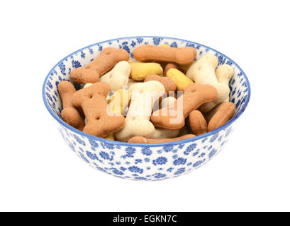 Biscuits pour chiens dans un bol en porcelaine bleu et blanc avec un design floral, isolé sur fond blanc Banque D'Images