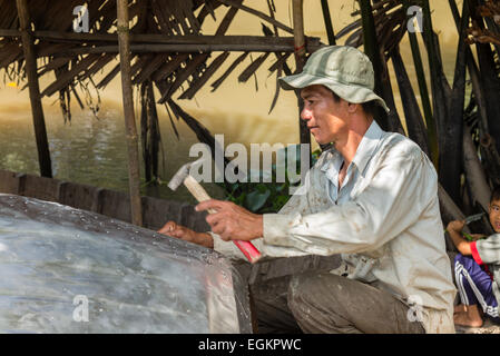 La réparation de pêcheur bateau dans la campagne agricole le long des canaux du Mékong dans le Delta du Mékong du Vietnam. Banque D'Images