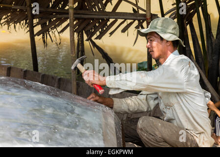 La réparation de pêcheur bateau dans la campagne agricole le long des canaux du Mékong dans le Delta du Mékong du Vietnam. Banque D'Images