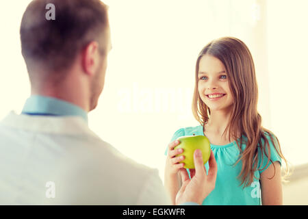 Médecin homme donnant une pomme pour smiling little girl Banque D'Images