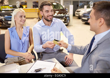 Couple heureux avec concessionnaire automobile à auto show ou salon Banque D'Images