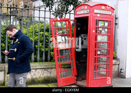 Homme avec un téléphone mobile en passant devant une cabine téléphonique près de Aldgate East London Banque D'Images