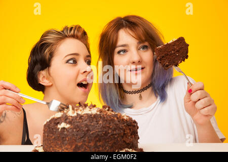 Deux jeune femme sur le point de manger un gros gâteau au chocolat. Banque D'Images