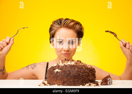 Jeune femme sur le point de manger un gros gâteau au chocolat. Banque D'Images