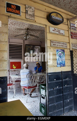 La Barbade bar intérieur, de murs en bois, rustique, les hommes assis à table, un retour à l'appareil photo, caméra, un avis sur les murs. Banque D'Images