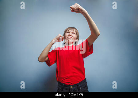 Garçon, adolescent, 12 ans, chemise rouge en montrant ses poings Banque D'Images