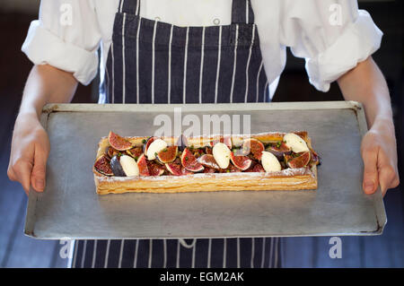 Bac de cuisine Chef holding Fig tarte avec du fromage et pistaches Banque D'Images