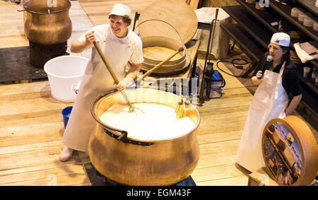 Un jeune couple s'agite un grand tva en cuivre pour fabriquer du fromage à l'Agriculture, Paris, France, le mercredi 25 février, 2015. Une femme parle au micro. Banque D'Images