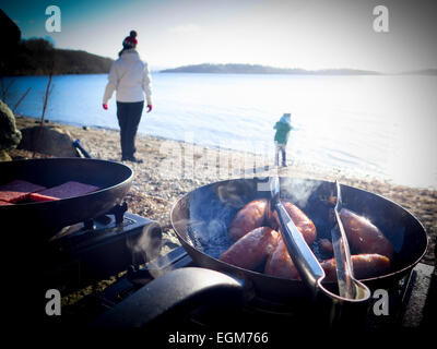 Faire cuire les saucisses à frire au bord du lac Banque D'Images